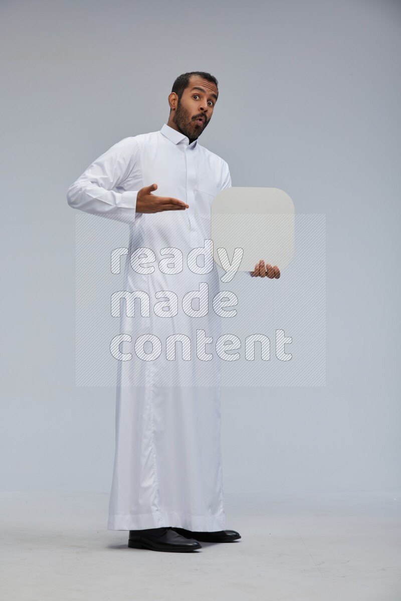 Saudi man wearing Thob standing holding social media sign on Gray background