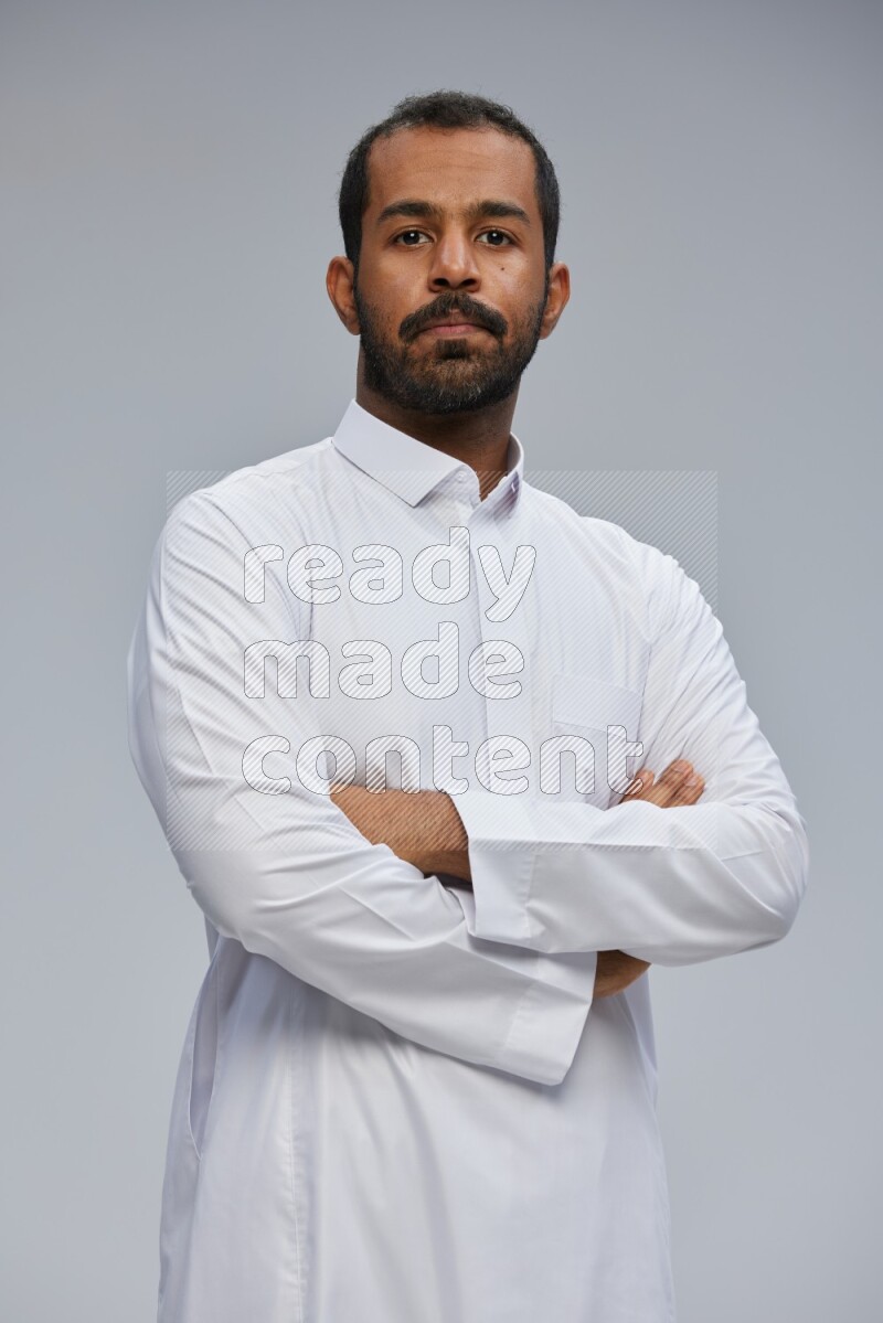 Saudi man wearing Thob standing with crossed arms on Gray background