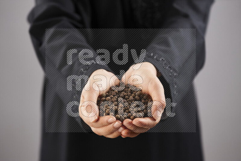 Woman in abaya holding different kinds of spices in different positions