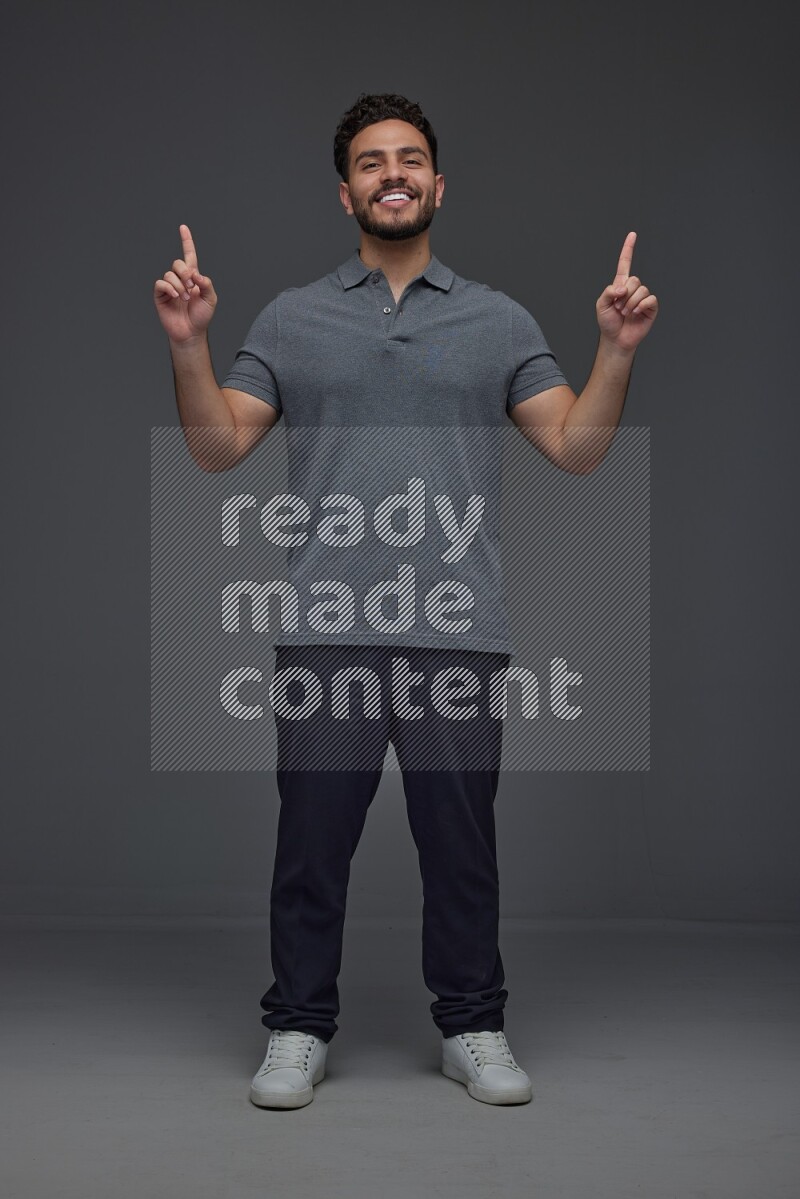 A man wearing casual standing and making multi hand gestures eye level on a gray background