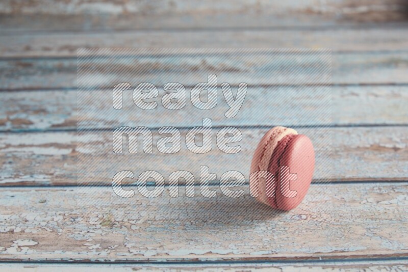 45º Shot of Pink Litchi Raspberry macaron on light blue wooden background