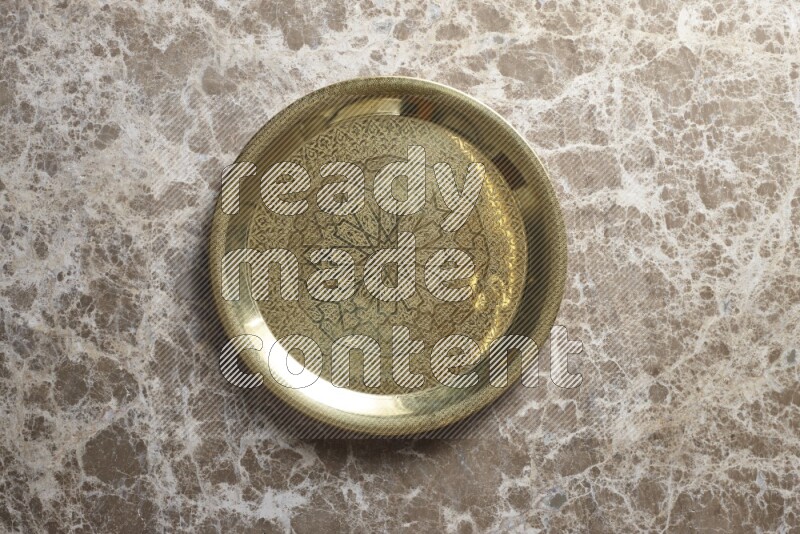 A golden metal tray on beige marble background