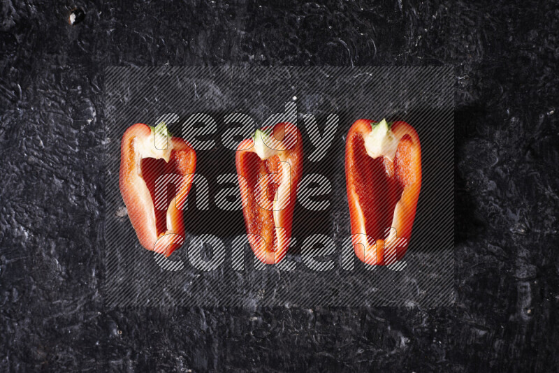 Red bell pepper slices on black background