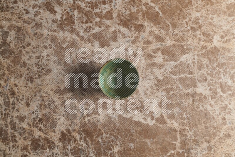 A dark green pottery bowl on beige marble background