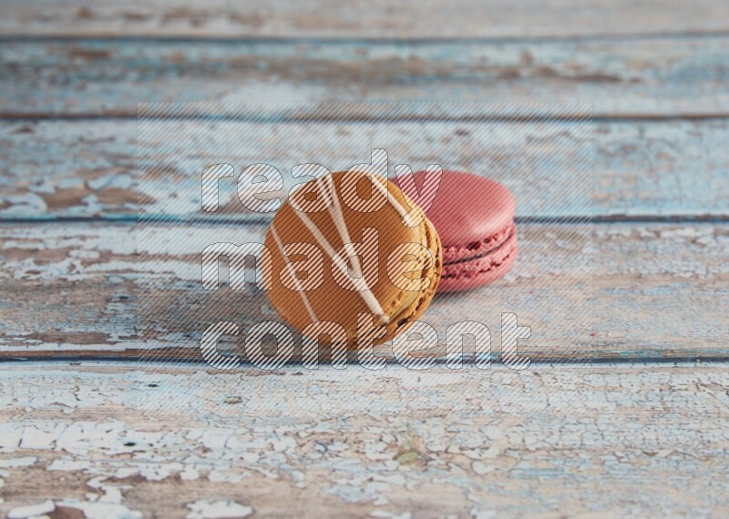 45º Shot of of two assorted Brown Irish Cream, and Pink Raspberry macarons on light blue background