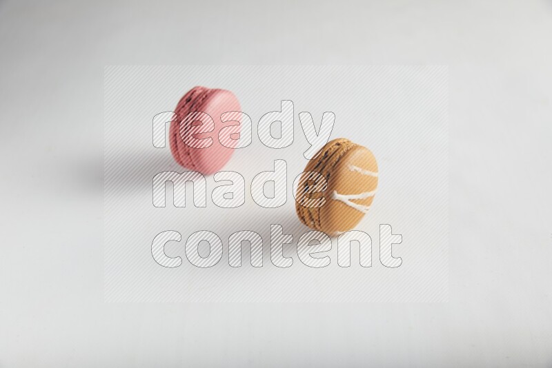 45º Shot of of two assorted Brown Irish Cream, and Pink Raspberry macarons on white background