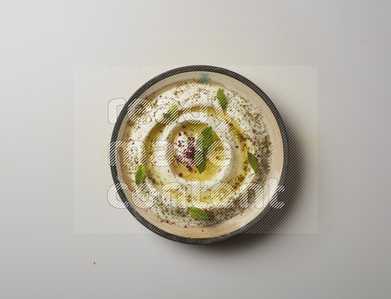 Lebnah garnished with zaater, mint & sumak in a pottery plate on a white background