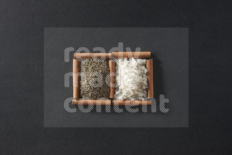 2 squares of cinnamon sticks full of white salt and cumin on black flooring