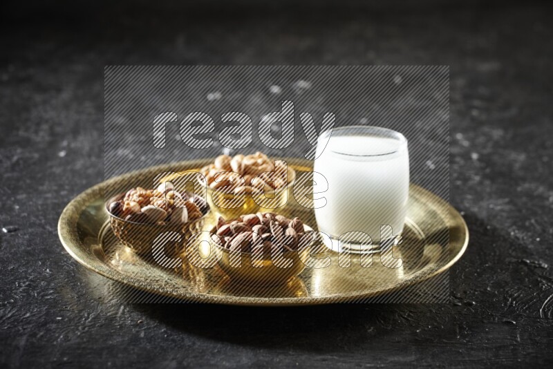 Nuts in metal bowls with sobya on a tray in dark setup
