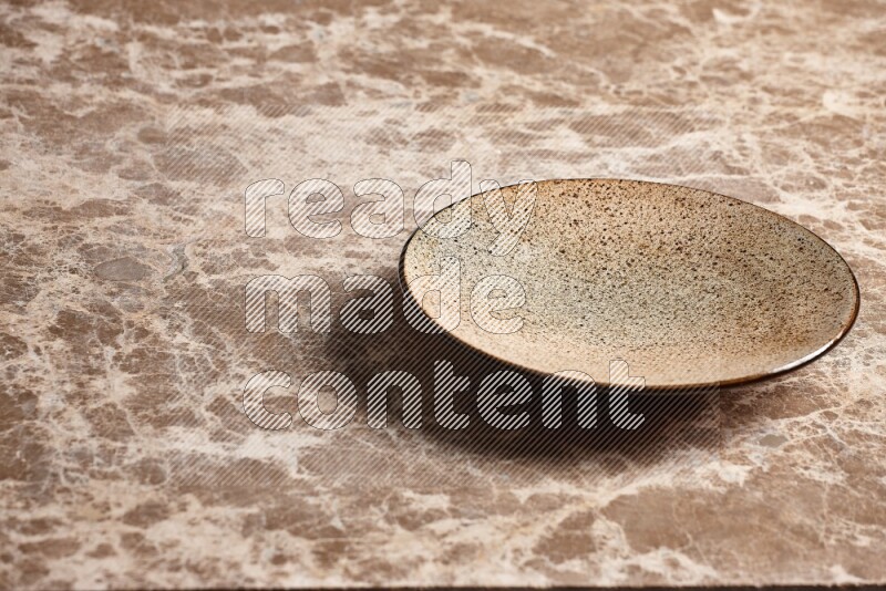 A multicolored pottery plate on beige marble background