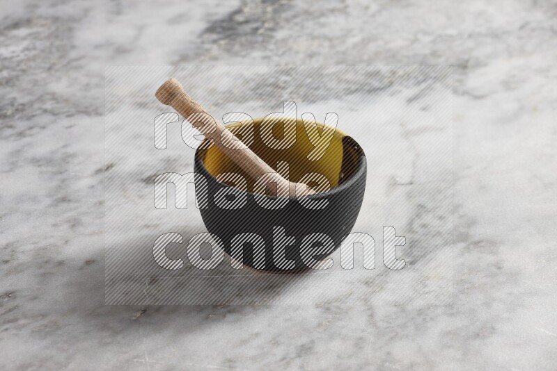 Multicolored pottery bowl with wooden honey dipper in it on grey marble background