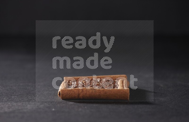 أربعة من أعواد القرفة مكونة شكل مربع بداخلها بذور الكتان علي خلفية سوداء