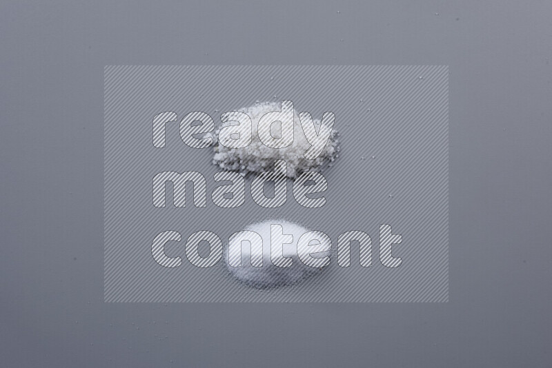 Bunches of table salt, coarse sea salt, fine himalayan salt and coarse himalayan salt on grey background