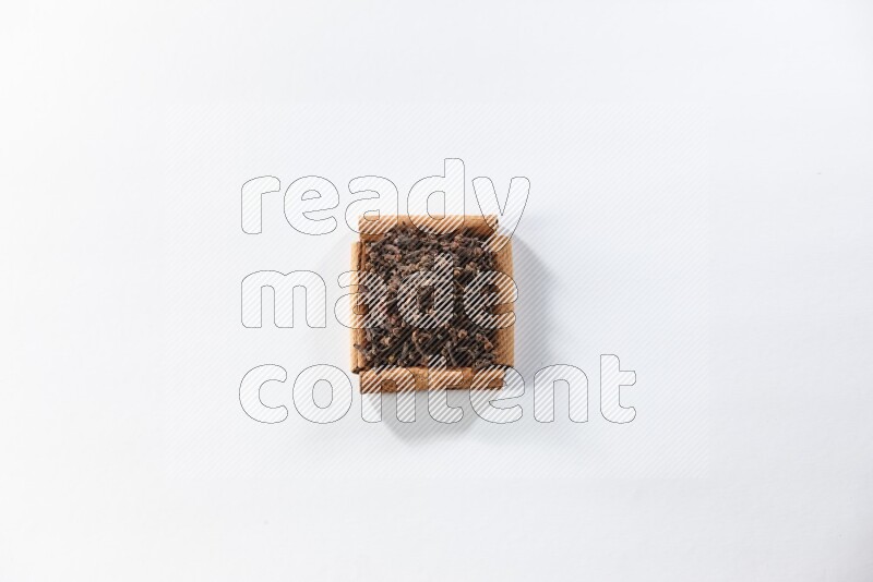 أربعة من أعواد القرفة مكونة شكل مربع بداخلها حبوب قرنفل علي خلفية بيضاء