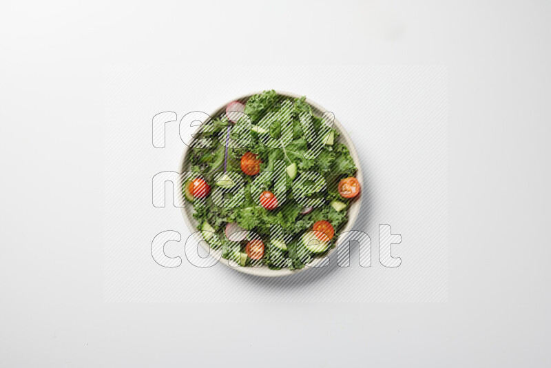 A bowl of fresh vegetables salad with kale leaves, cherry tomatoes, sliced radishes and sliced cucumber on a white background