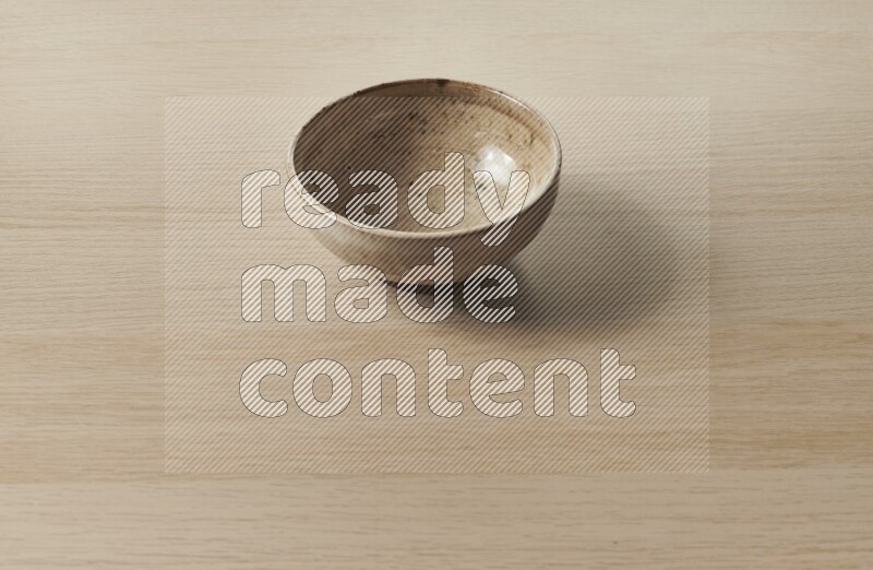 A beige pottery bowl on light wooden background