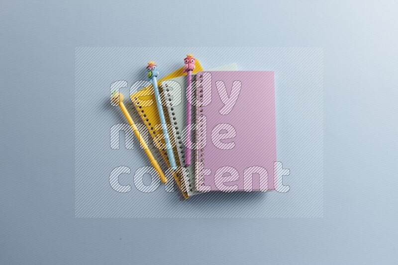 Multicolored notebooks with different school supplies on blue background