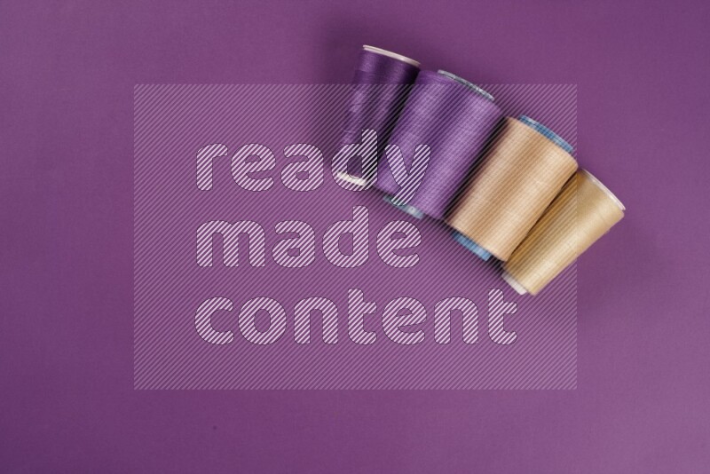 مجموعة من أدوات الخياطة والتفصيل باللون البيج على خلفية أرجوانية