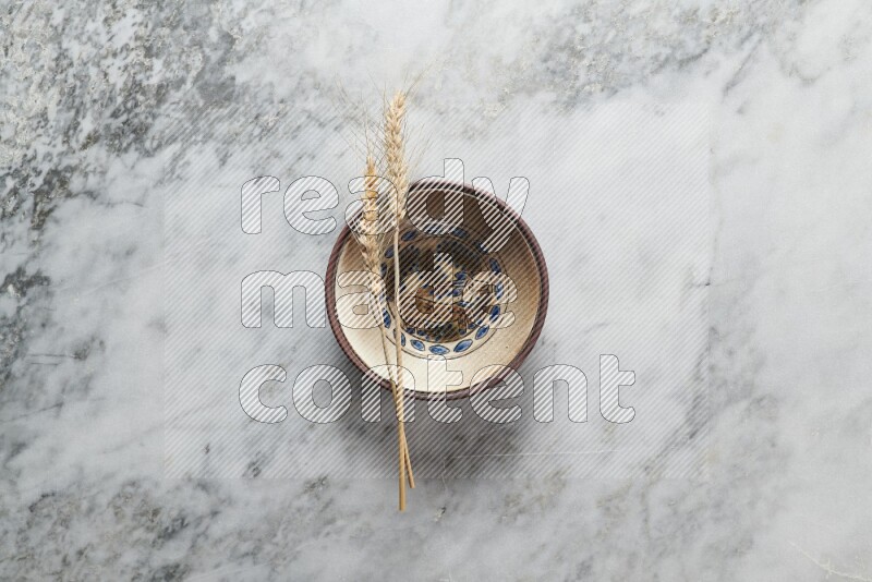 Wheat stalks on decorative pottery plate on grey marble background