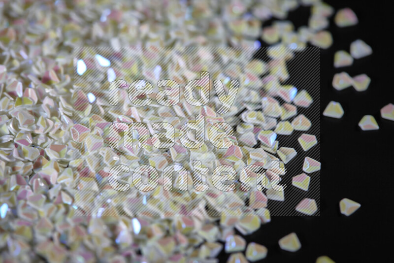 قطع صغيرة بلاستيكية ملونة للزينة متناثرة على خلفية سوداء