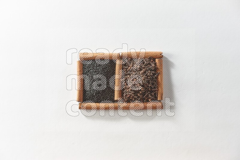 2 squares of cinnamon sticks full of cloves and black seeds on white flooring