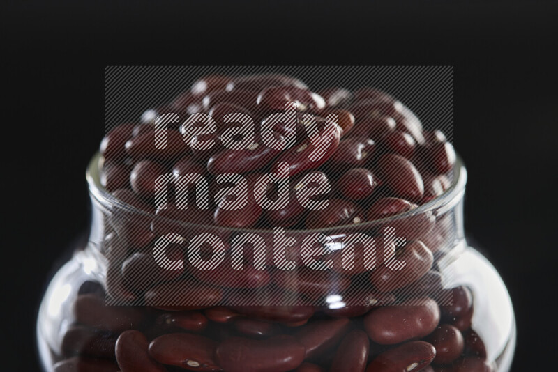 Red kidney beans in a glass jar on black background