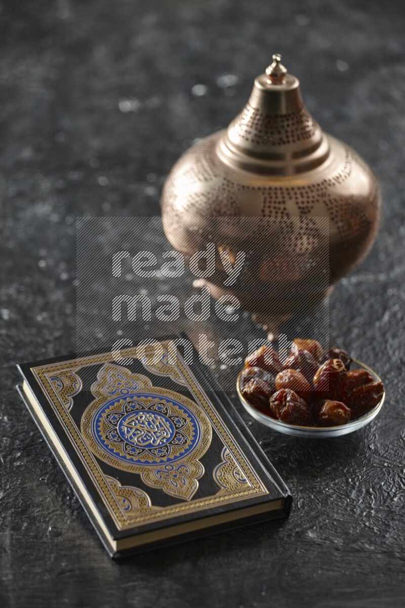 A golden lantern with different drinks, dates, nuts, prayer beads and quran on textured black background