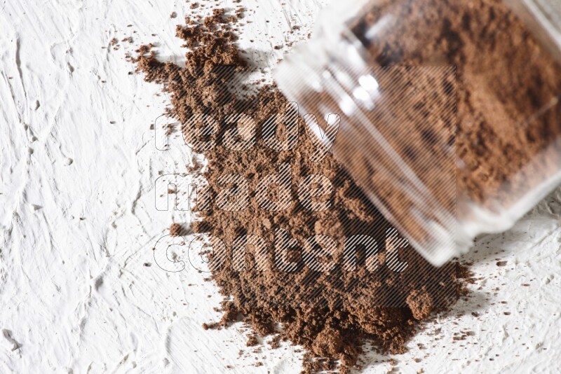 وعاء زجاجي مقلوب ممتلئ ببودرة القرنفل على أرضية بيضاء