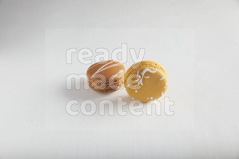 45º Shot of of two assorted Brown Irish Cream, and Yellow Piña Colada macarons on white background