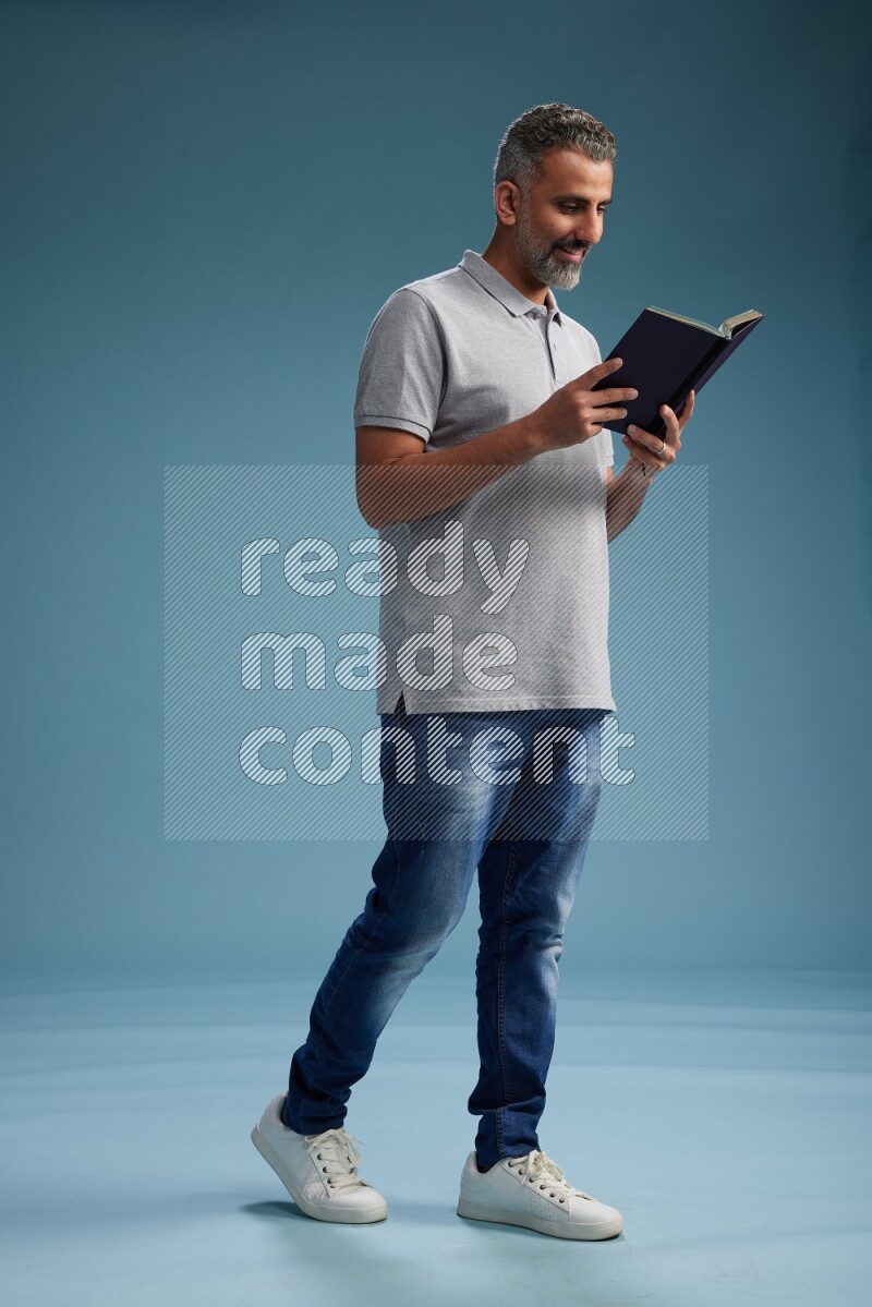 Man Standing reading book on blue background