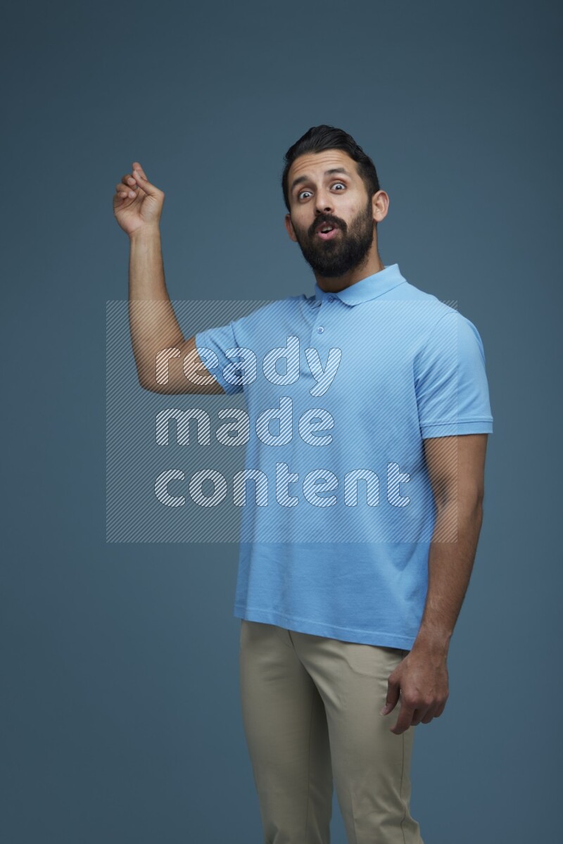 A man pointing  in a blue background wearing a Blue shirt