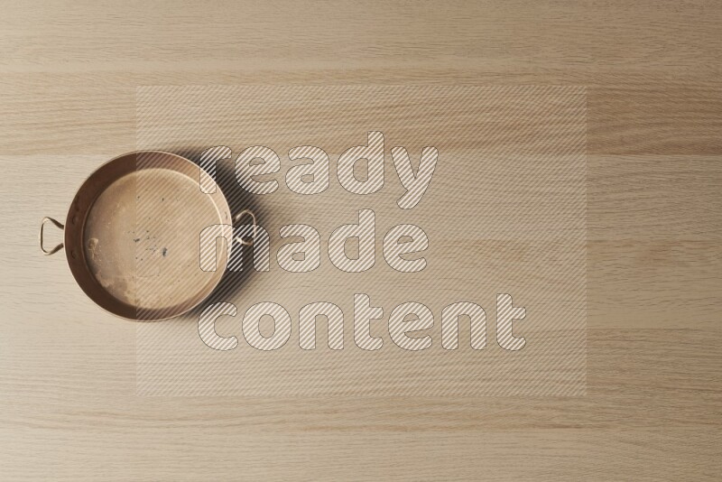 A small copper pan on light wooden background