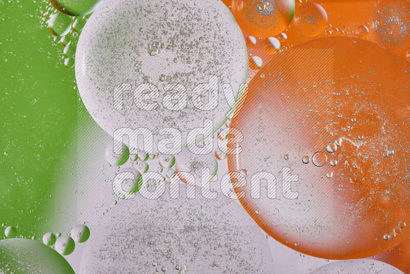 Close-ups of abstract oil bubbles on water surface in shades of orange, green and white