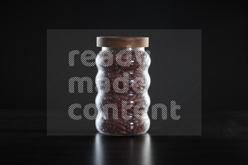 Red kidney beans in a glass jar on black background