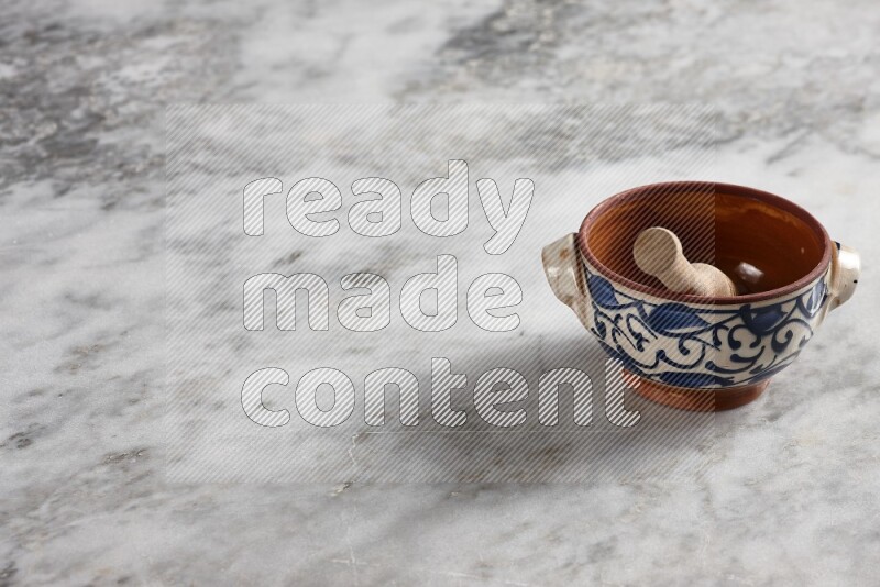 Decorative pottery pot with wooden honey dipper in it on grey marble background