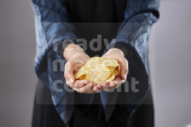 Woman in abaya holding different kinds of snacks in different positions