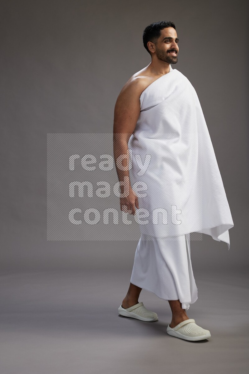A man wearing Ehram Standing Interacting with the camera on gray background