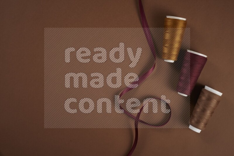 A red collection of sewing and tailoring tools arranged on a brown background