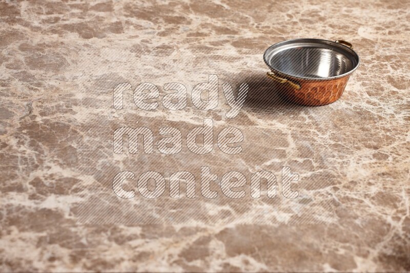 A small copper pot on beige marble background