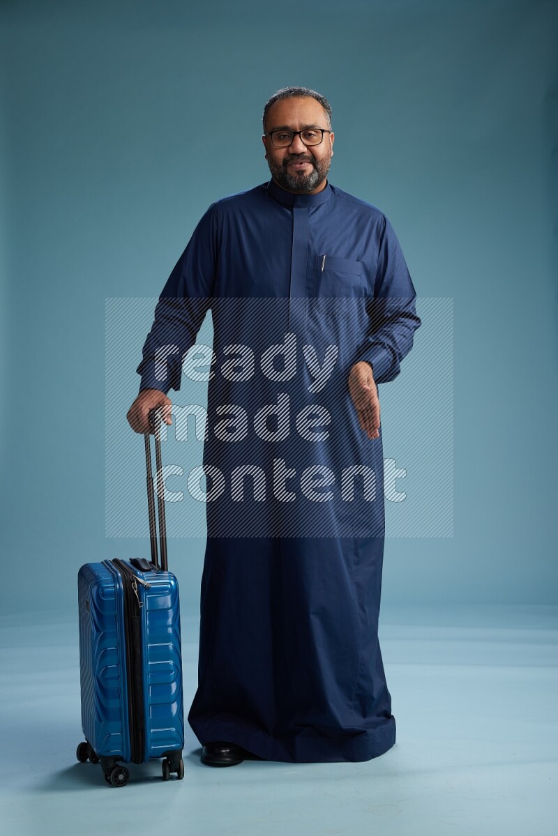 Saudi Man without shimag Standing pulling travel bag on blue background