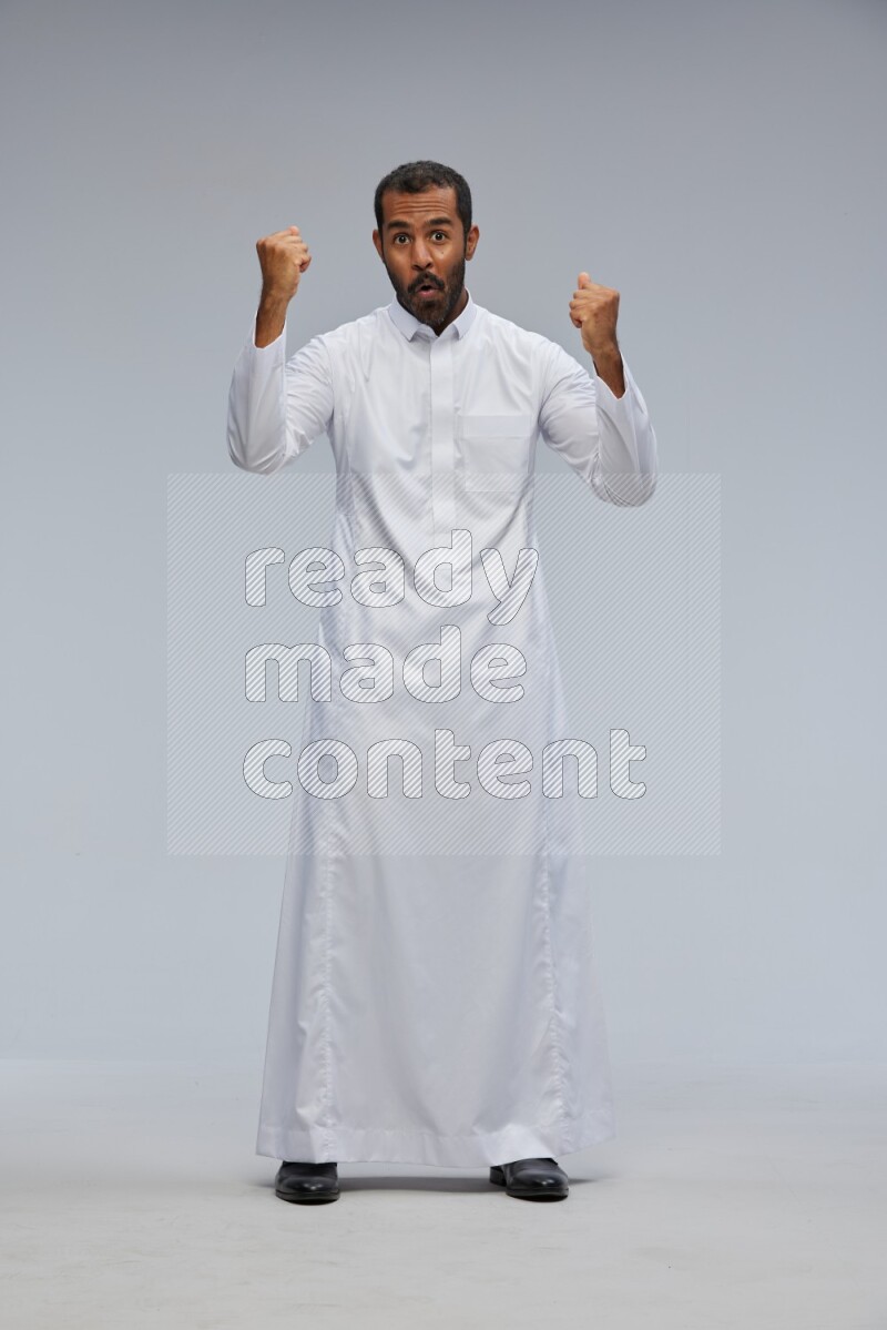 Saudi man Wearing Thob standing interacting with the camera on Gray background