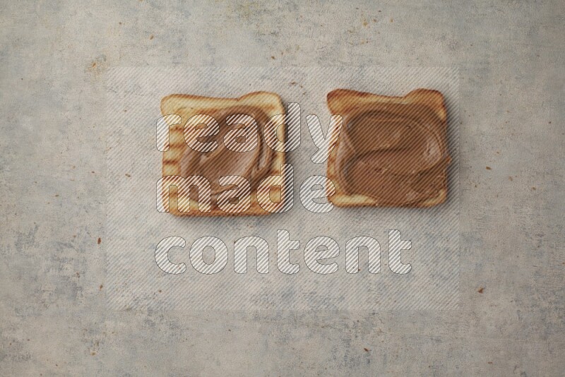 Creamy peanut butter on a toasted white toast slices on a light blue textured background