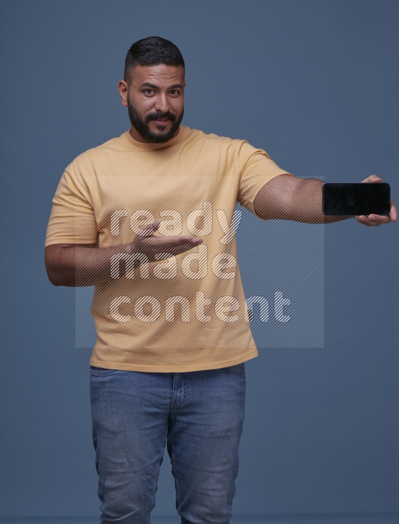 A man Showing His Smart Phone on Blue Background wearing Orange T-shirt