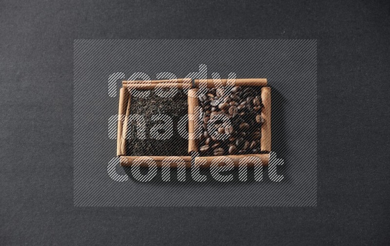 مربعان من أعواد القرفة ممتلئان بحبوب القهوة والشاي الأسود علي خلفية سوداء