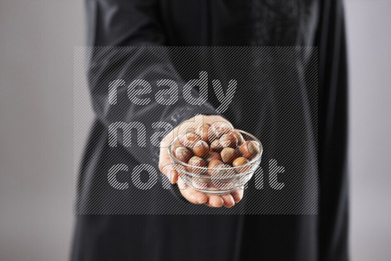 Woman in abaya holding different kinds of nuts in different positions