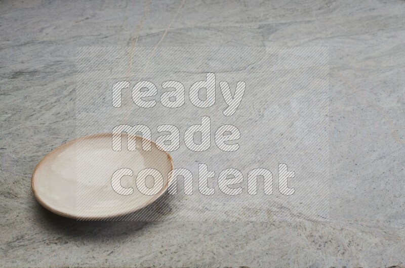 A beige pottery plate on grey marble background