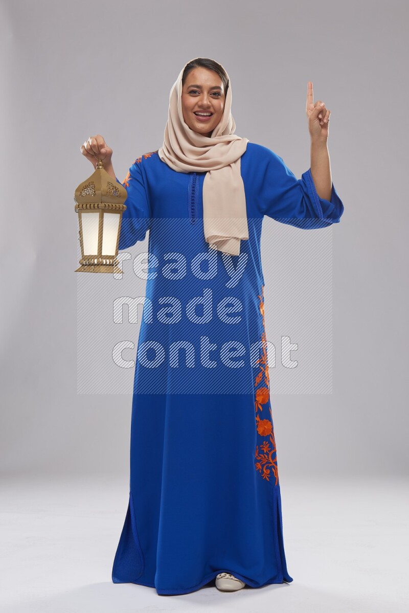 A Saudi woman standing wearing Jalabeya holding a lantern