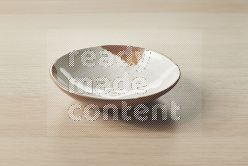 A multicolored pottery plate on light wooden background
