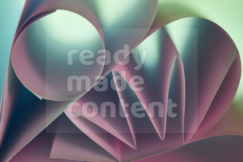 An artistic display of paper folds creating a harmonious blend of geometric shapes, highlighted by soft lighting in green and pink tones