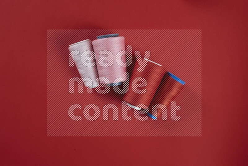 A pink and red collection of sewing and tailoring tools arranged on a red background